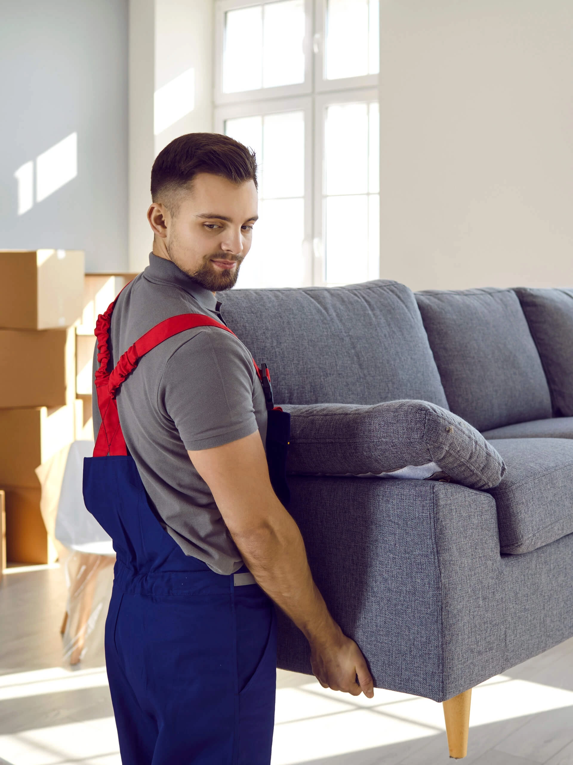 Umzug, Entrümpelung und Haushaltsauflösung in Nürnberg – Mann hebt Sofa, im Hintergrund Kartons